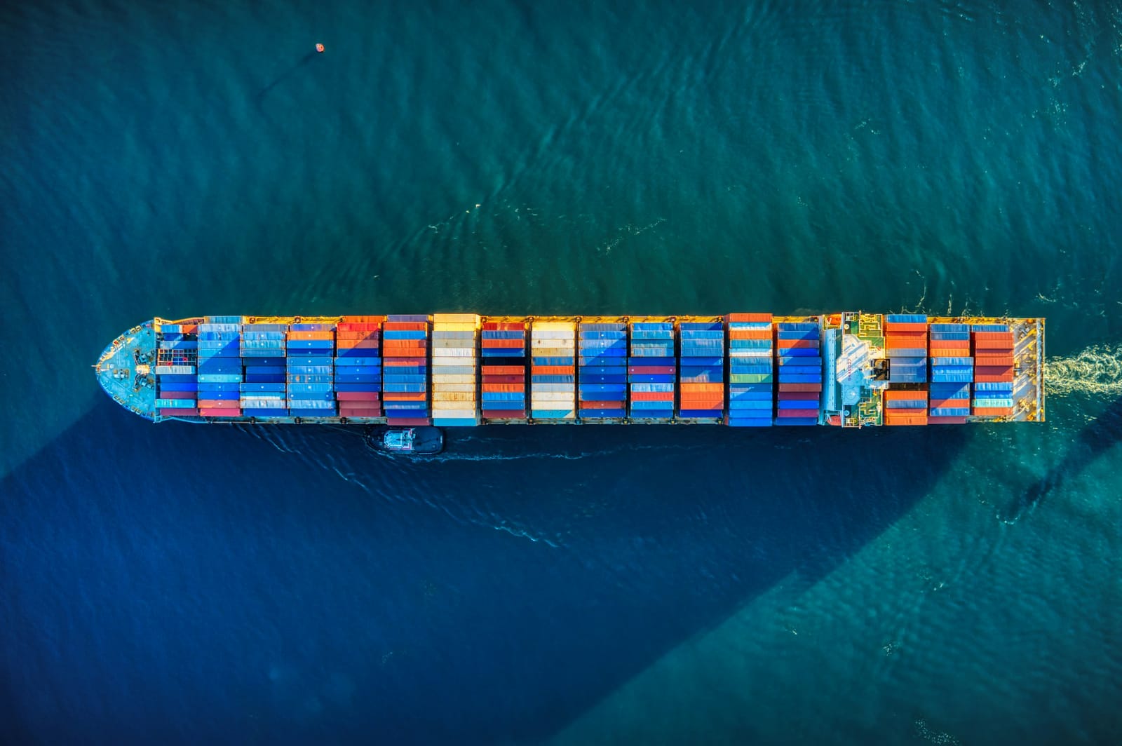 Aerial view of a container ship under way, containers stacked in colour blocks